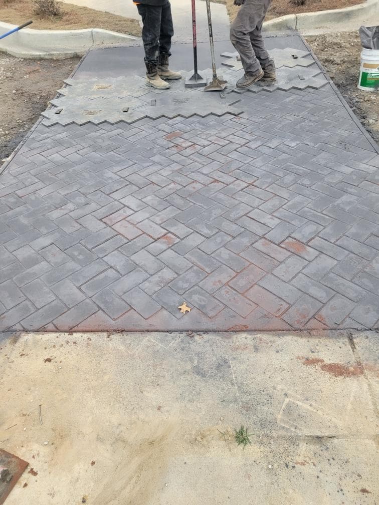 JSW crew pressing herringbone brick stamp into fresh colored concrete